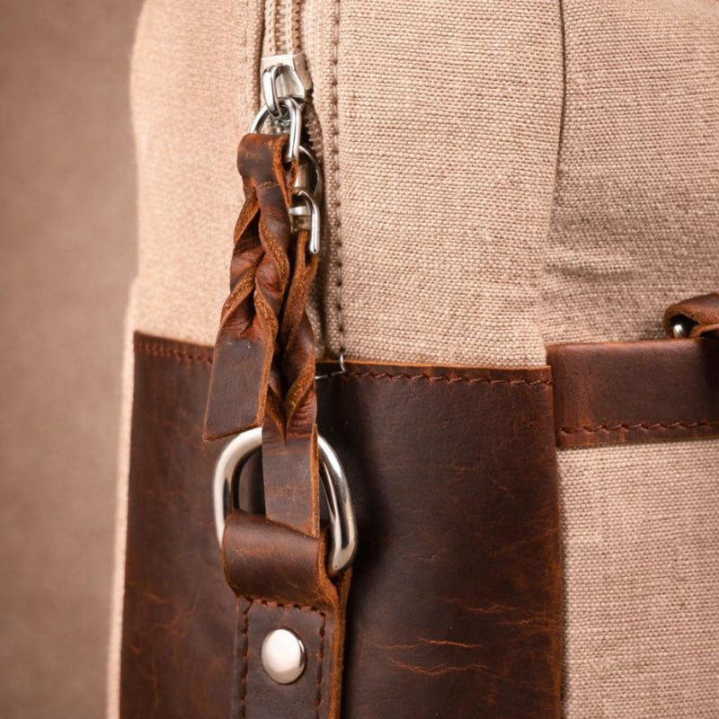 Close-up of a brown canvas & leather bag with a keychain attached.