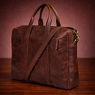 Brown leather bag with a shoulder strap on a wooden surface and brown background