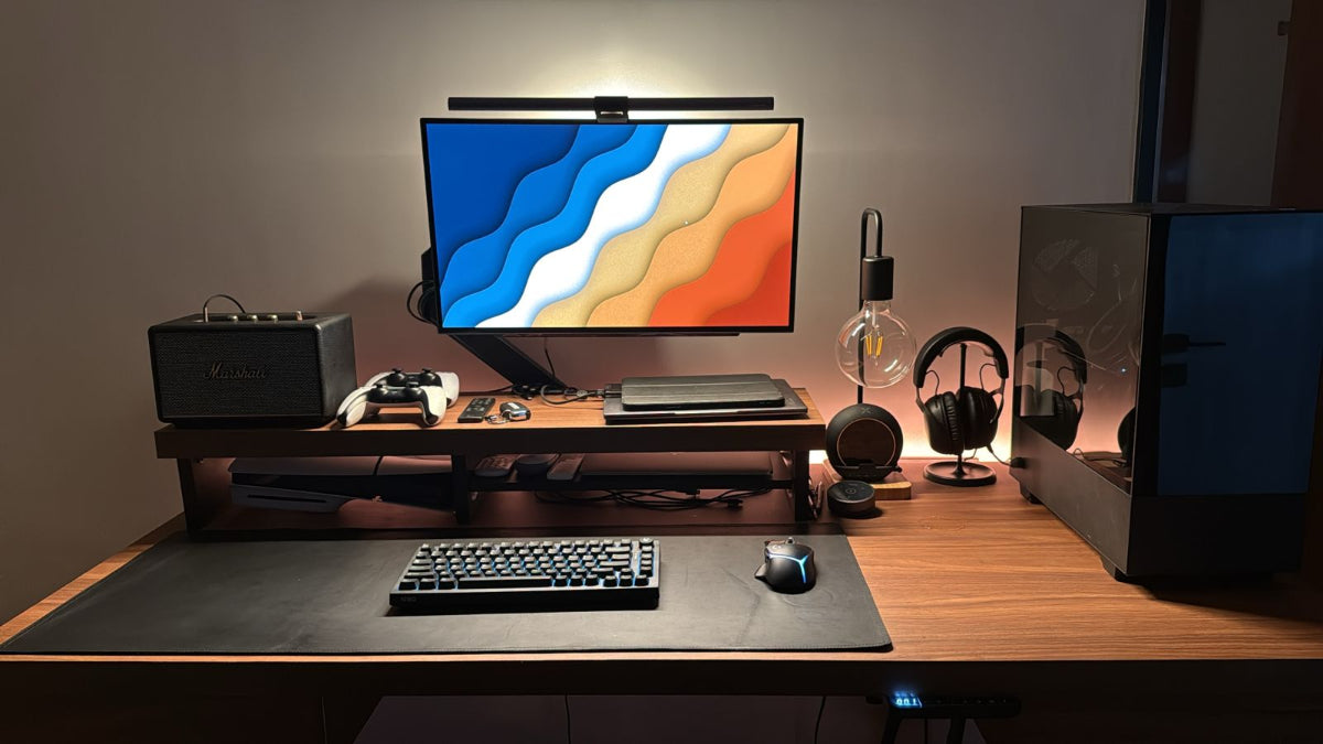 Modern home office desk setup with computer monitor, keyboard, mouse, desk mat and speakers.