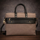 Brown canvas travel bag with black accents on a wooden surface and dark background