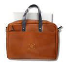 Tan leather bag with black handles on a white background