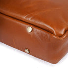 Close-up of a Tan leather suitcase with gold rivets on a white background