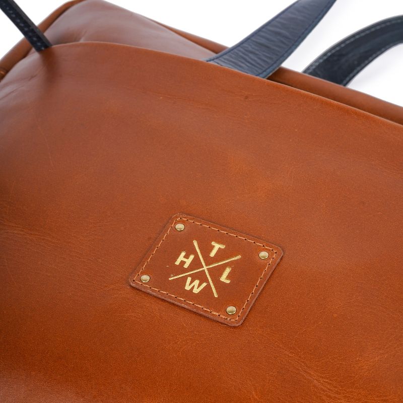 Tan leather bag with a brand logo on a white background