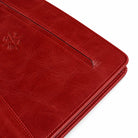 Close-up of red leather portfolio zipper and embossed logo.