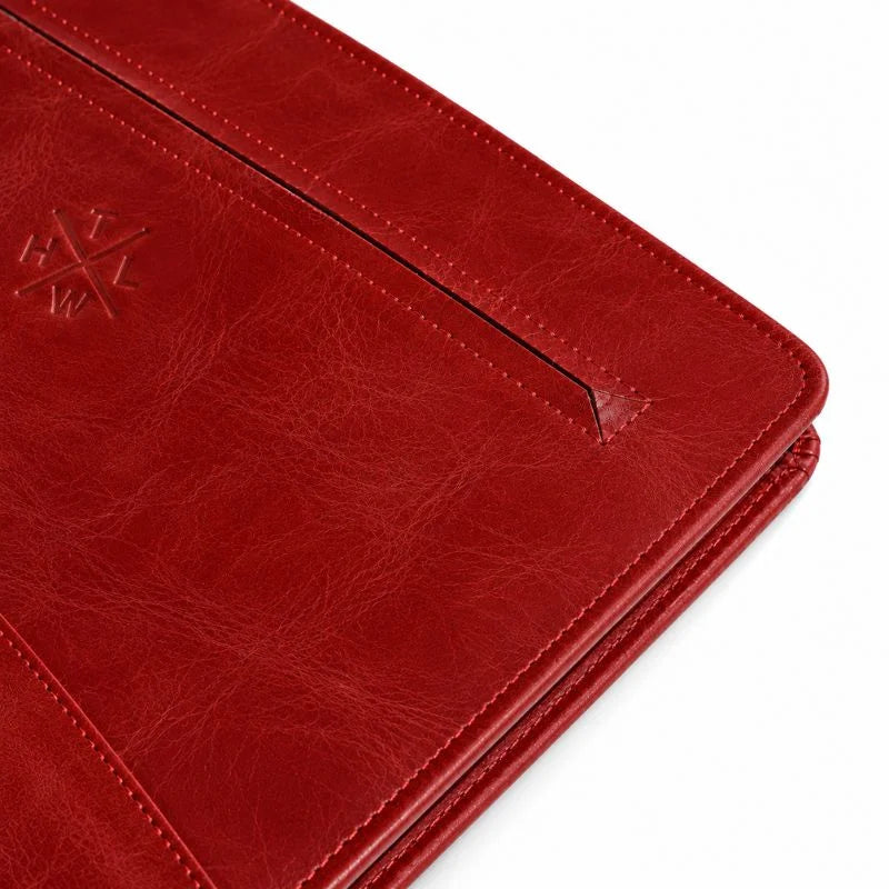 Close-up of red leather portfolio zipper and embossed logo.