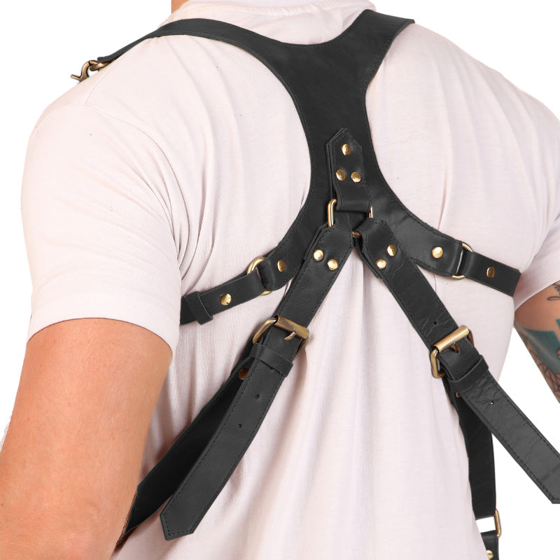 Rear side of black leather camera harness with cross straps and sturdy hardware.